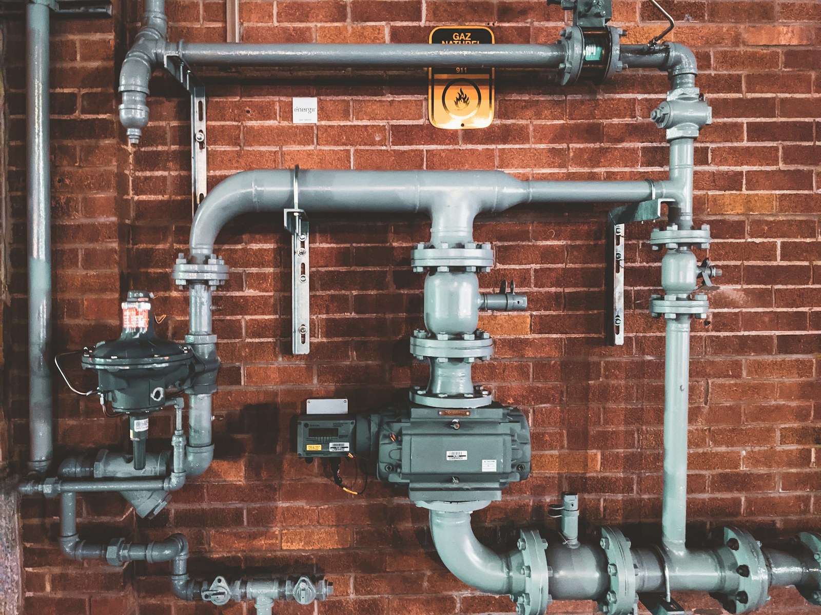 Exposed pipes, valves and gauges on a brick wall